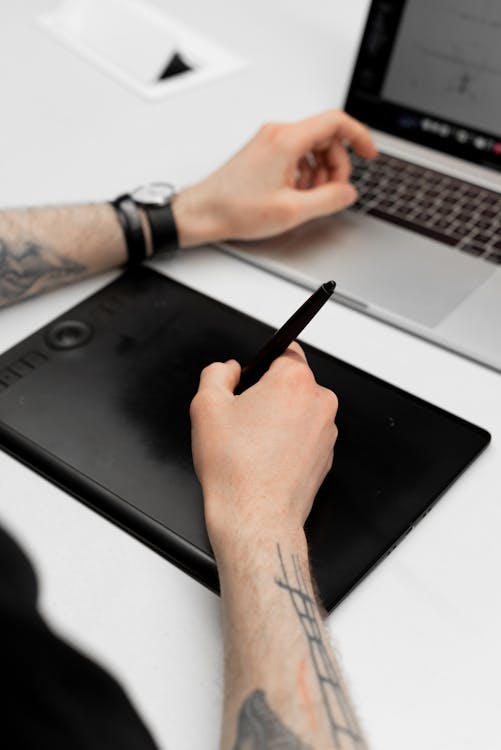 Designer using tablet and laptop with Canva AI features for graphic design