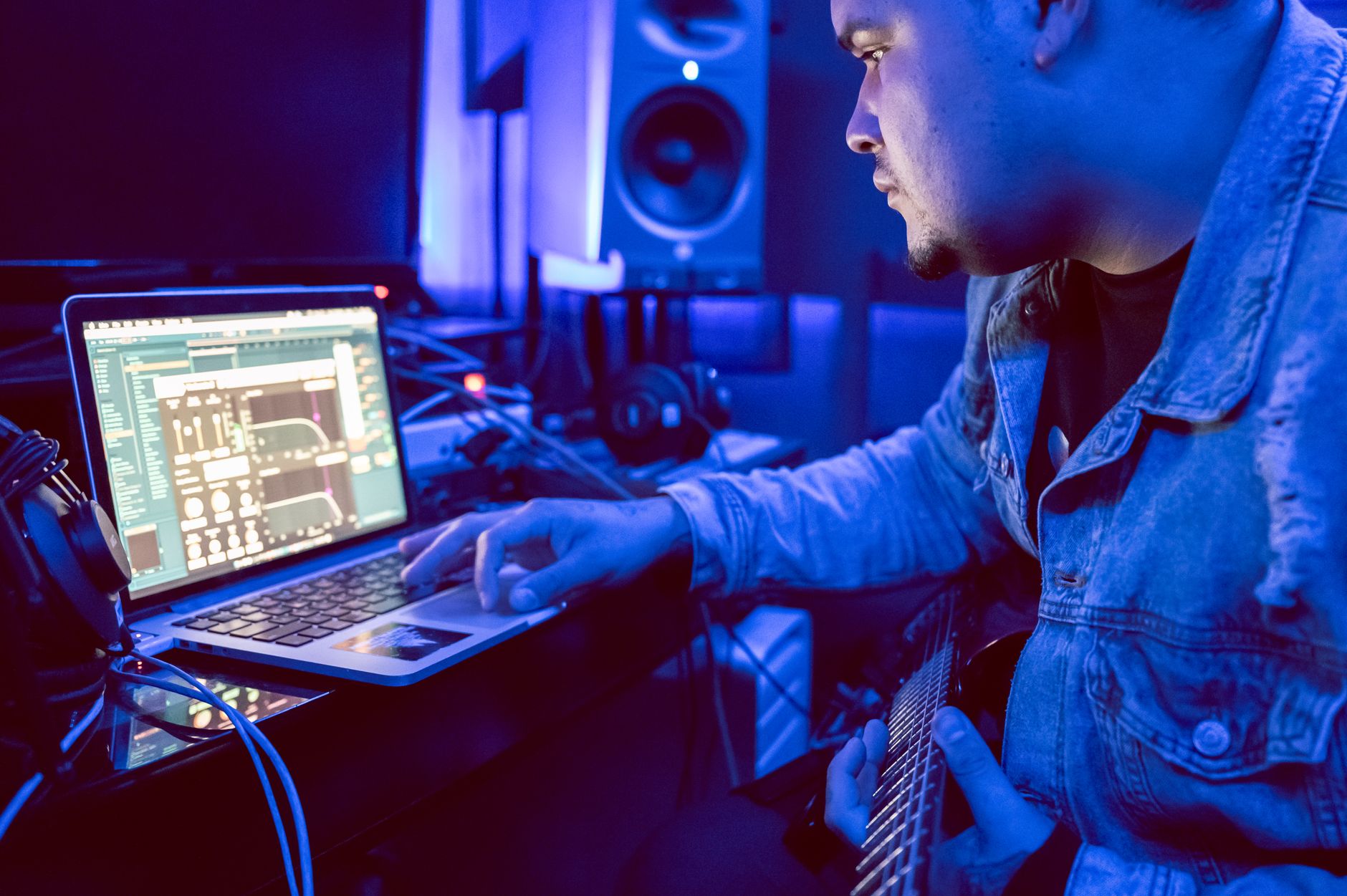 Suno AI Review 2026: Can This AI Music Generator Create Real Indian Songs? Young musician using laptop for music production in recording studio.