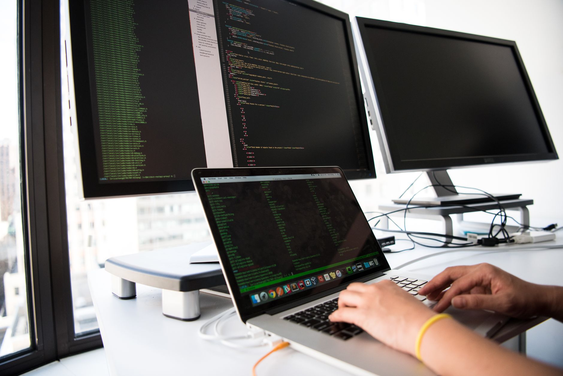 Developer coding on multiple monitors using AI tools — Cursor vs Claude Code comparison for Indian developers