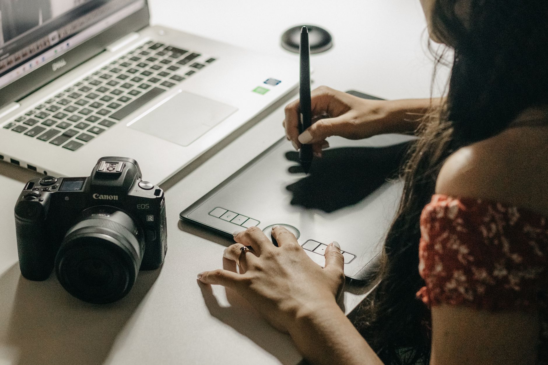 Designer using graphics tablet with laptop and camera for digital content creation - comparing Canva vs Adobe Express vs Microsoft Designer