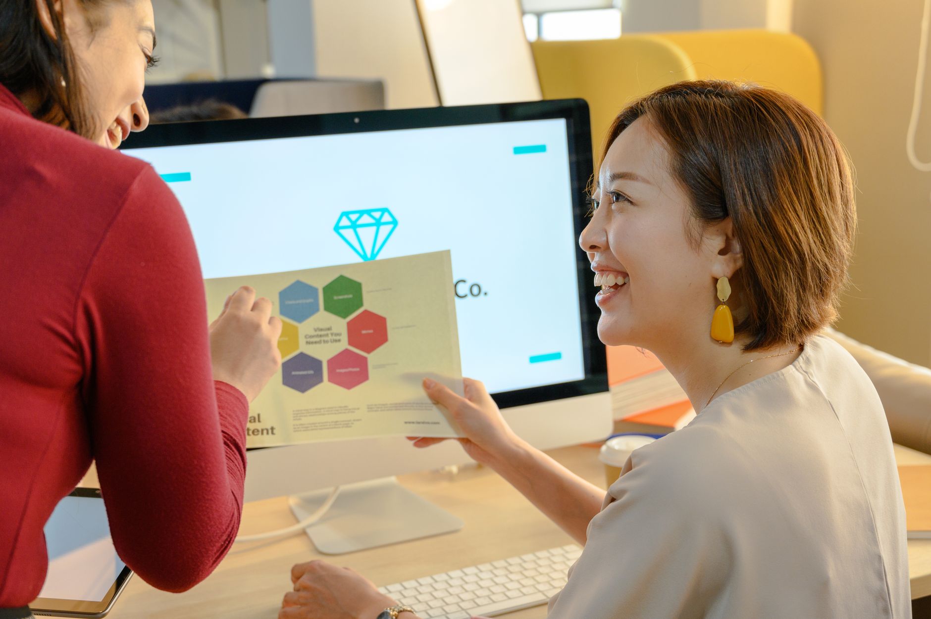 Team discussing visual design content on computer screen in modern office - choosing the right design tool