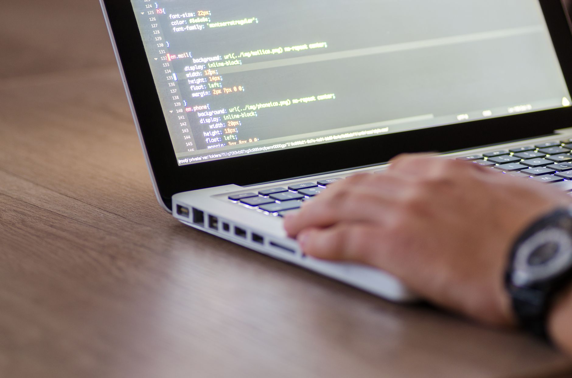 Developer coding on laptop with HTML interface representing AI-powered app building workflow