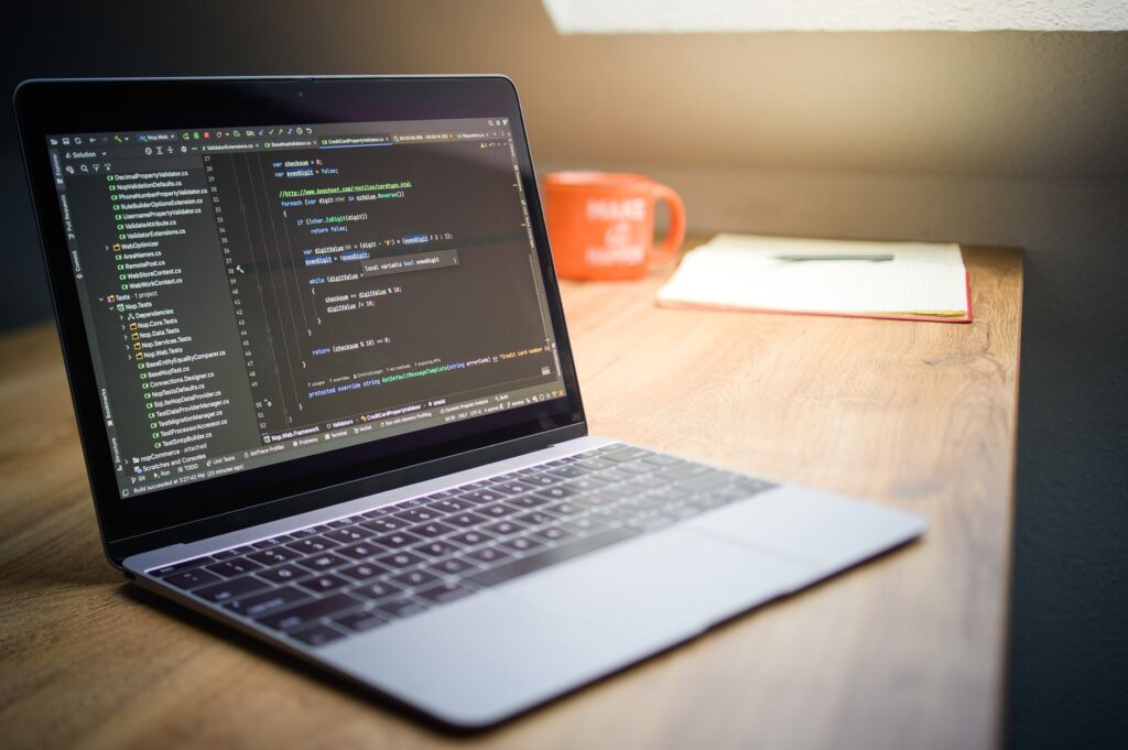 Developer laptop workspace with notebook and mug showing code editor setup